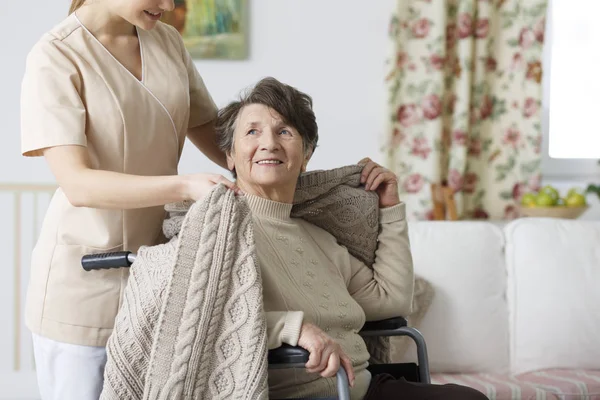 Verzorger bedekking senior vrouw met een deken — Stockfoto