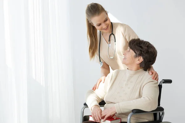 Woman on wheelchair and caregiver smiling — Stock Photo, Image