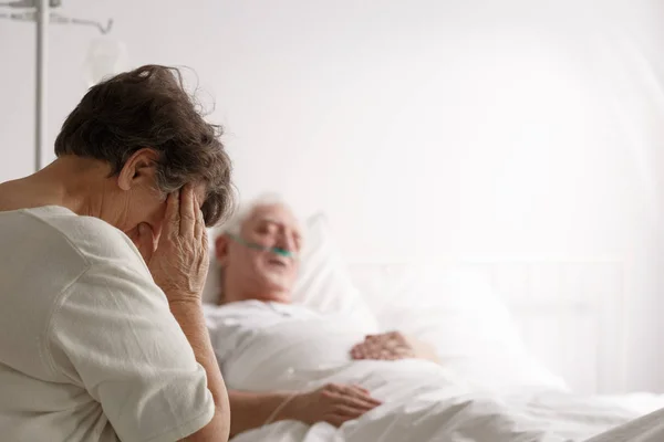 Frau sitzt neben sterbendem Ehemann — Stockfoto