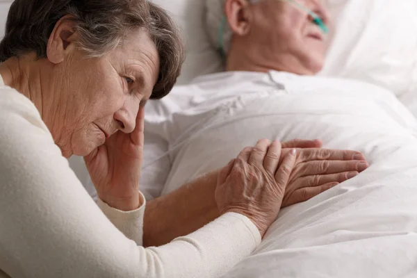 Vrouw die stervende man's hand Rechtenvrije Stockfoto's