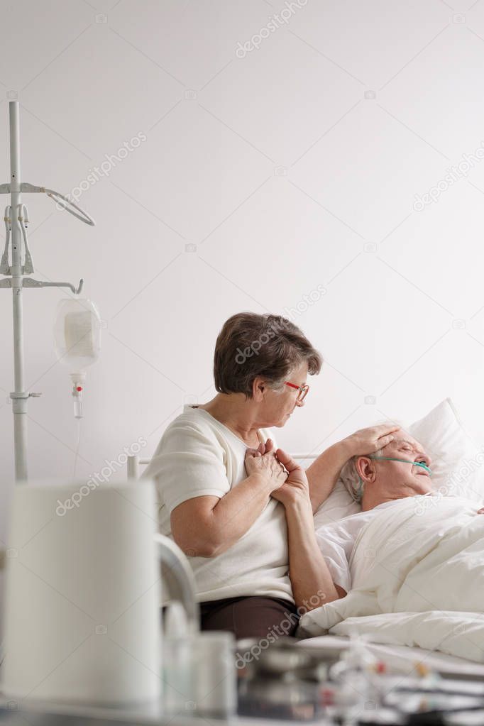 Woman holding dying husband's hand