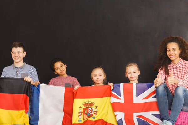 Niños sonrientes sosteniendo banderas — Foto de Stock