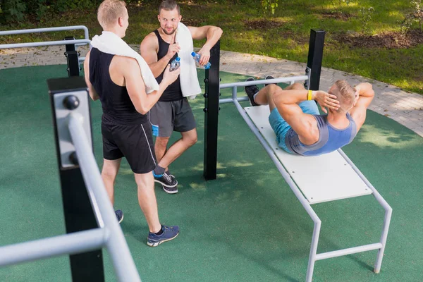 Hombre haciendo ejercicio y sus amigos descansando —  Fotos de Stock