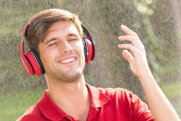 Hombre escuchando música bajo la lluvia — Foto de Stock