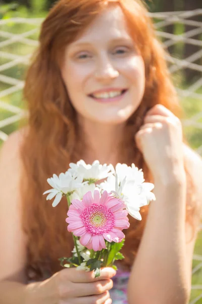 Usmívající se zázvor žena s květinami — Stock fotografie