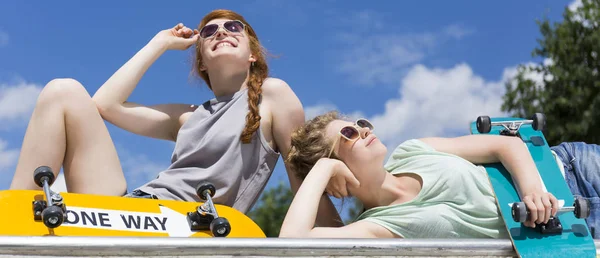 Meninas relaxadas banhos de sol com skates — Fotografia de Stock