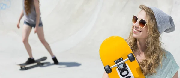 Женщина в солнечных очках держит скейтборд — стоковое фото