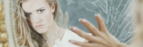 Woman touching broken mirror