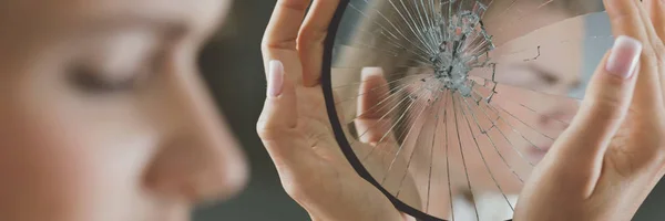 Woman holding broken mirror