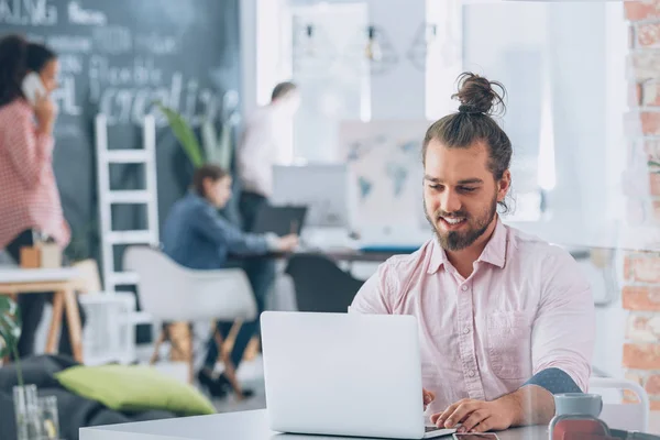 Sorridente uomo barbuto aziendale utilizzando il computer portatile — Foto Stock