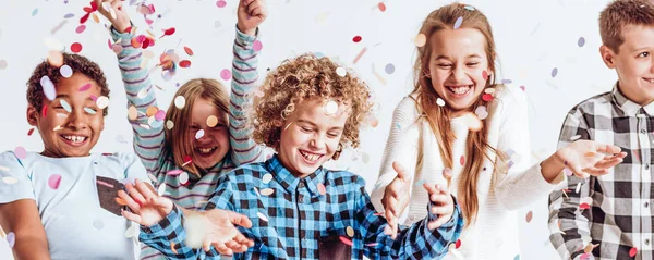 Niños sonrientes jugando con confeti —  Fotos de Stock