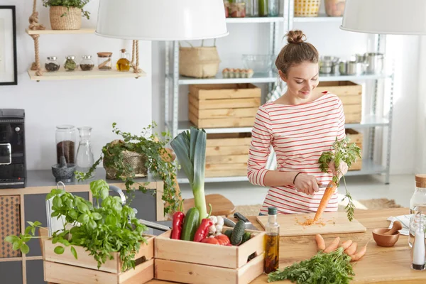 Mujer pelando una zanahoria en la cocina — Foto de Stock