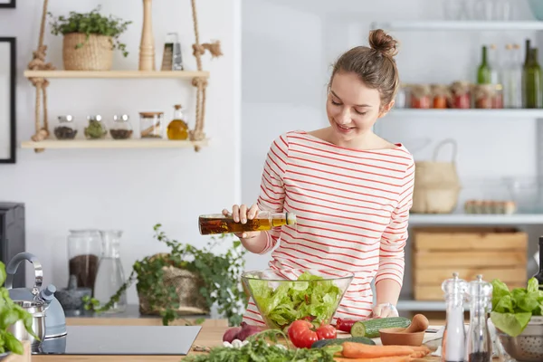 Женщина добавляет оливки в салат — стоковое фото