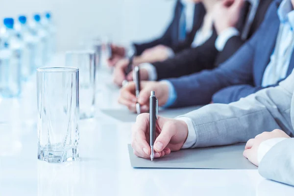 Mensen schrijven met pennen tijdens conferentie — Stockfoto