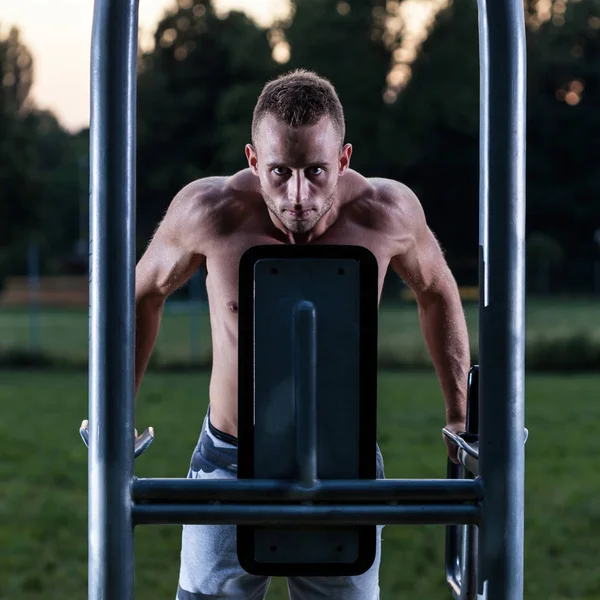 Musculoso hombre tirando hacia arriba en la máquina de ejercicio — Foto de Stock