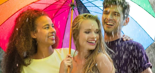 Amigos felices bajo paraguas colorido — Foto de Stock