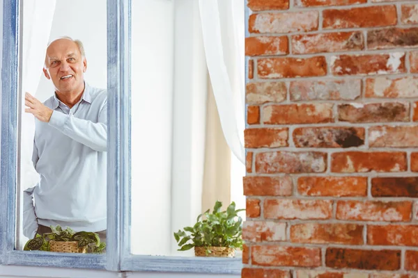 Starší muž dívá oknem — Stock fotografie