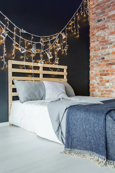 Bed with decoration next to brick wall — Stock Photo, Image