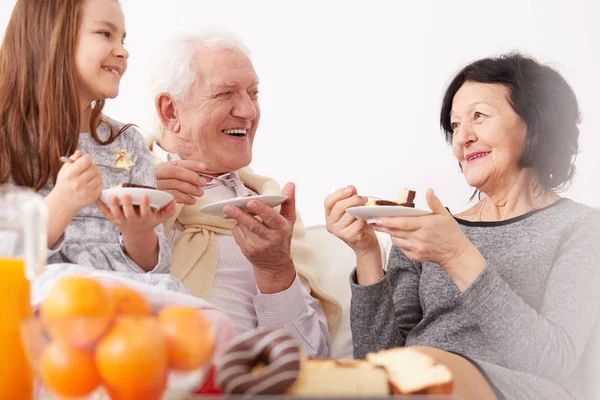 Abuelos y nieta comiendo pastel — Foto de Stock