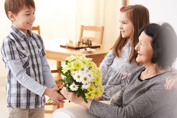 Nieto dando flores a la abuela — Foto de Stock