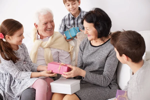 Petits-enfants donnant des cadeaux aux grands-parents — Photo