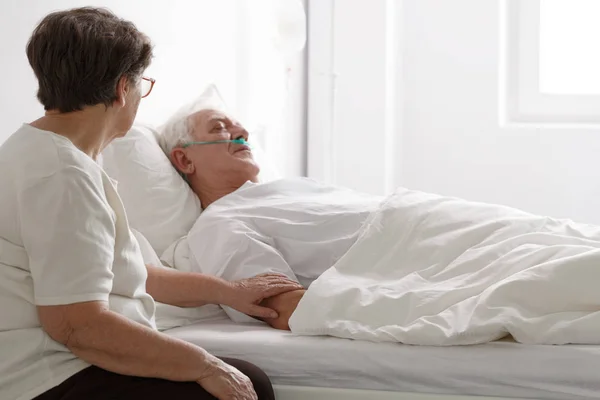 Man in een coma en zijn vrouw naast hem zitten — Stockfoto
