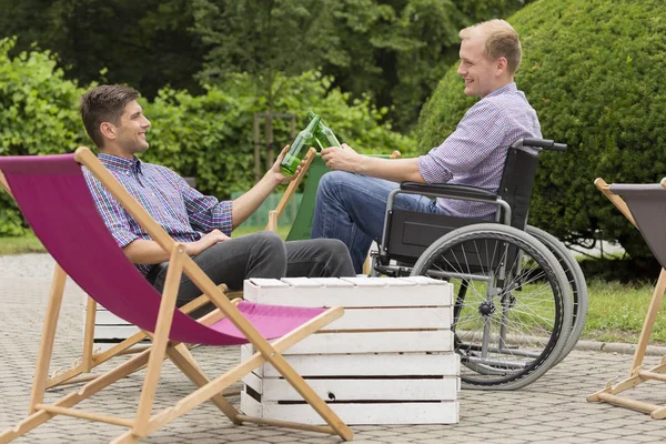 Disabled man drinking beer with friend — Stock Photo, Image