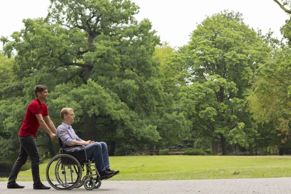 Man pushing disabled person on wheelchair — Stock Photo, Image