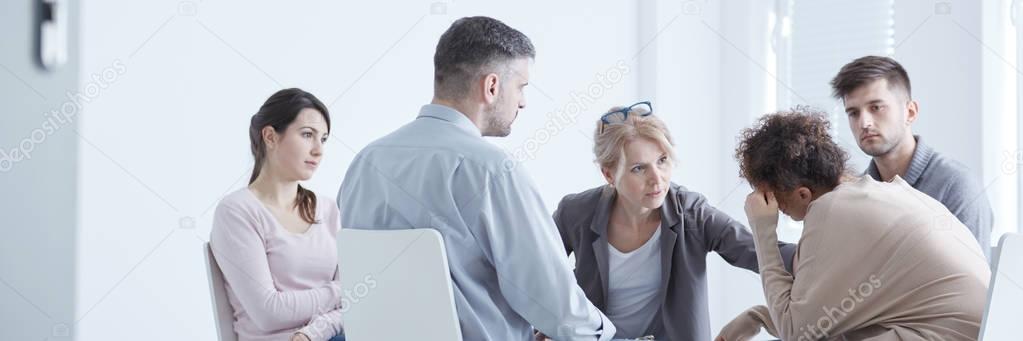 Rehab group therapist comforting woman