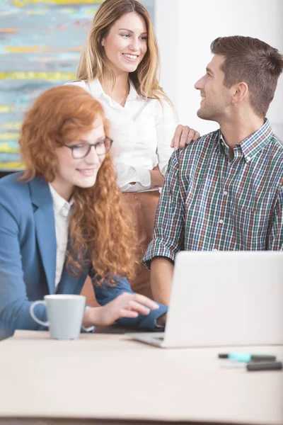 Collaboratori felici che si riuniscono intorno al computer portatile — Foto Stock