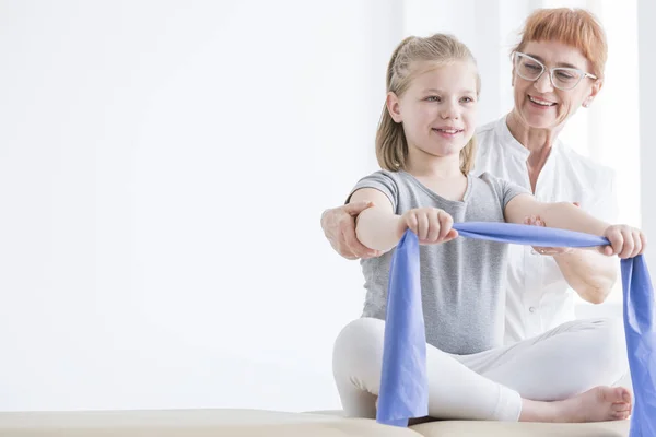 Little girl stretching rubber tape — Stock Photo, Image