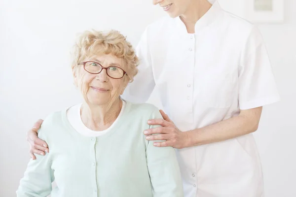Verpleegkundige hugs lachende oudere dame — Stockfoto