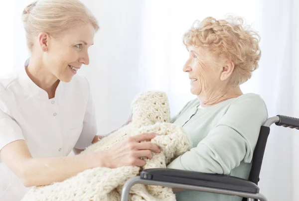 Sorridente volontario copre donna anziana — Foto Stock