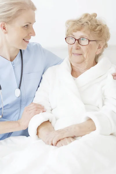 Медсестра разговаривает с больной старухой. — стоковое фото