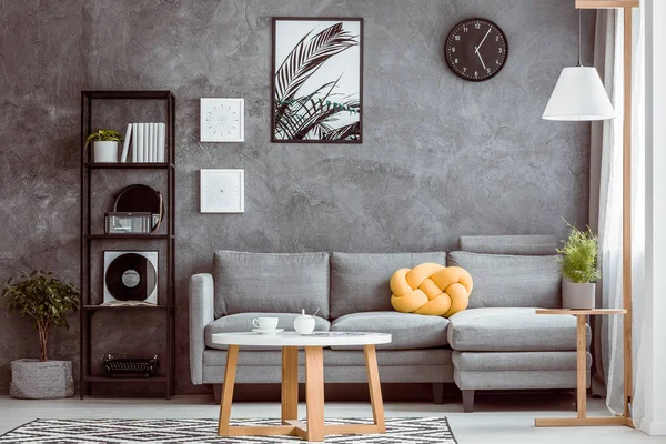 Svart klocka ovanför grå soffan — Stockfoto