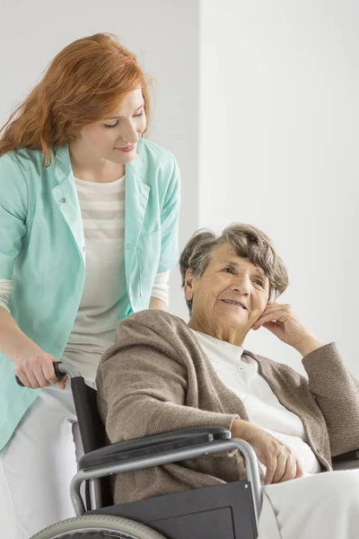 Junge Krankenschwester kümmert sich um Senioren Stockbild