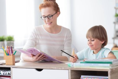 Çocuk kitabından egzersizleri yapıyor