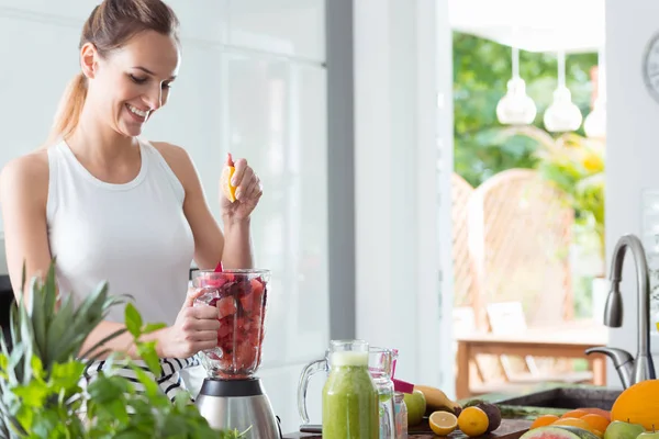 Lächelnde Frau presst Orangensaft — Stockfoto