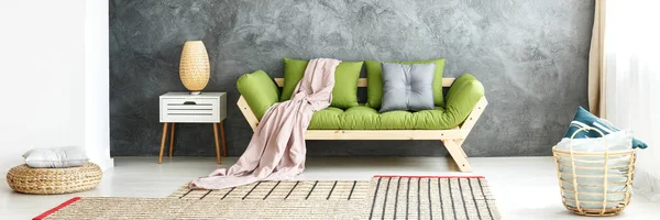 Grünes Sofa gegen strukturierte Wand — Stockfoto