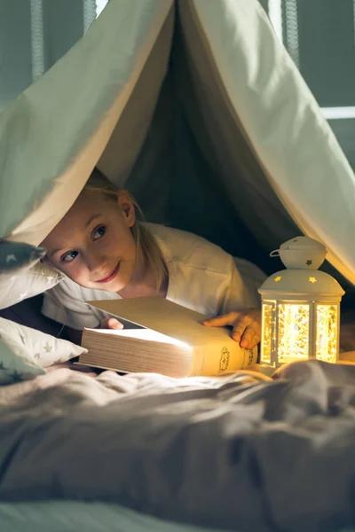 Child reading book in tent — Stock Photo, Image