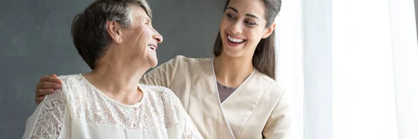 Pflegerin umarmt lächelnde ältere Frau — Stockfoto