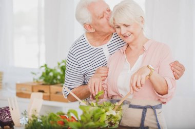 Çizgili gömlekli yaşlı adam karısını öpüyor