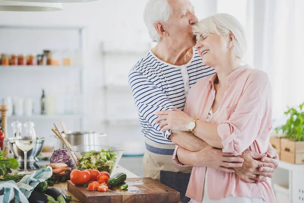 Büyükbaba hugs ve öper gülümseyen büyükanne