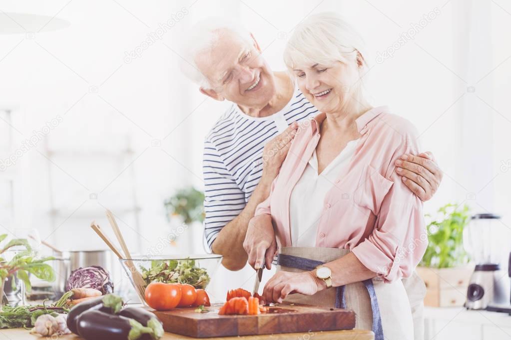 Elder woman is cutting tomatoes