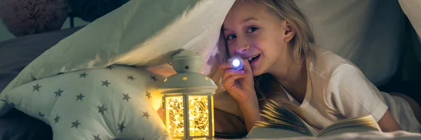 Smiling girl reading with lantern
