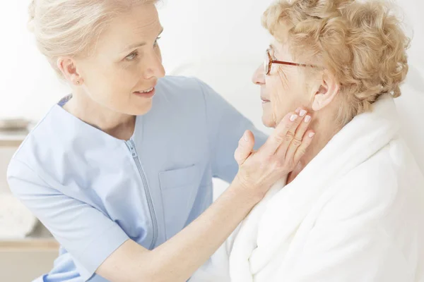 Vänliga sjuksköterska tröstande äldre kvinna — Stockfoto