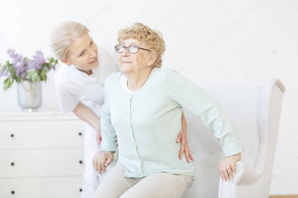 Young caregiver assisting smiling lady