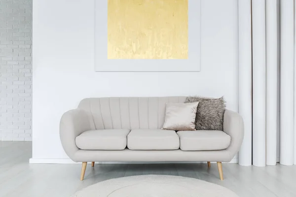 Золотая живопись над серым диваном — стоковое фото