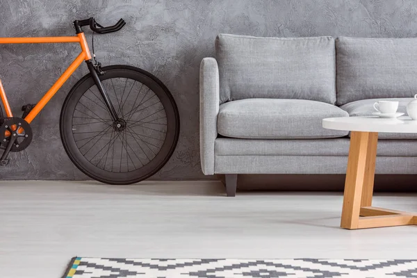 Bicicletta urbana e divano grigio — Foto Stock