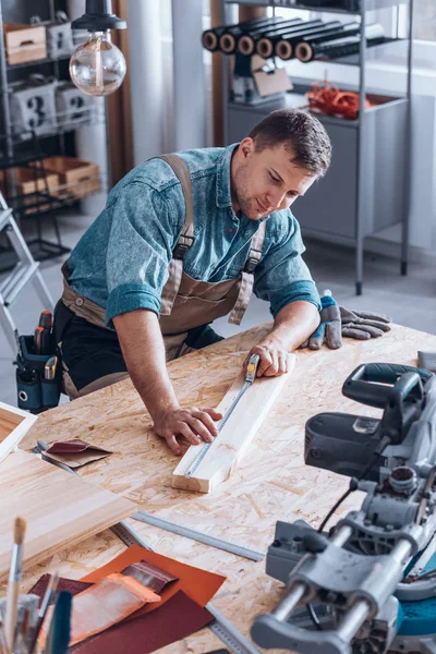 Moderno carpintero que mide tablón de madera —  Fotos de Stock